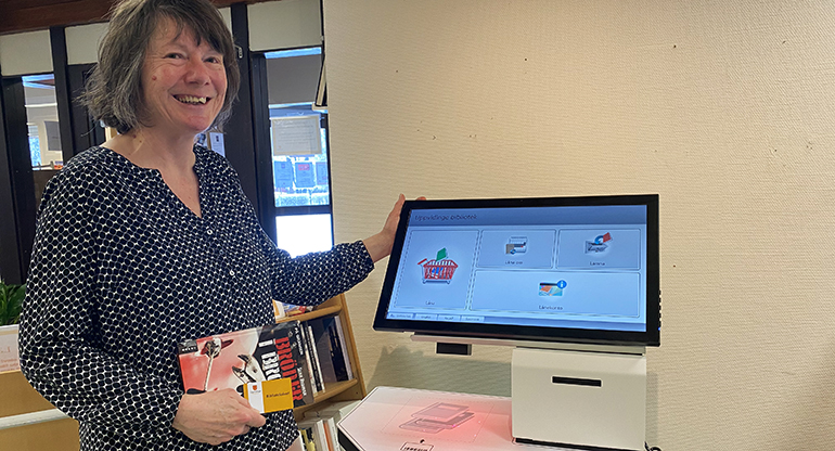 Bibliotekarie Sabine Helmerding visar den nya självbetjäningsautomaten på Åseda bibliotek.