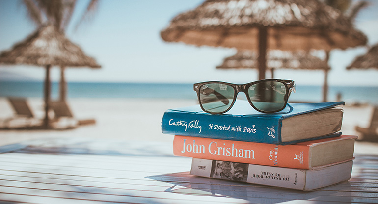 Tre böcker och ett par solglasögon. Foto.