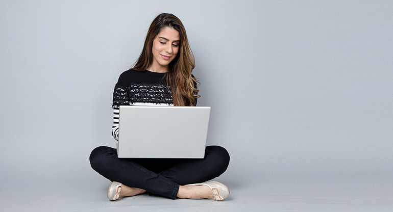 En kvinna med en dator i knät. Foto.